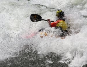 man wearing yellow and red wet suit  while doing activity kayak thumbnail