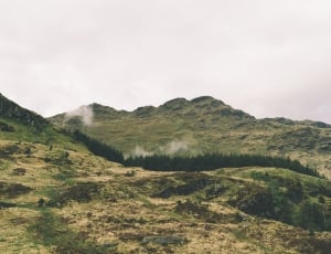 green trees on mountains under gray cloudy sky during daytime thumbnail