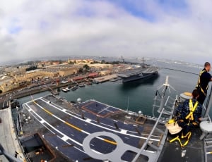 two men on metal frame of a Jet Carrier during daytime in fisheye photography thumbnail