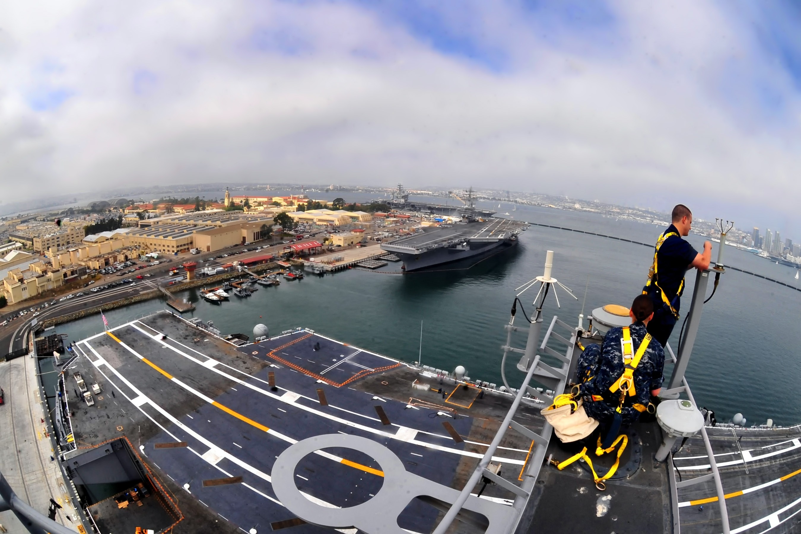 two men on metal frame of a Jet Carrier during daytime in fisheye photography