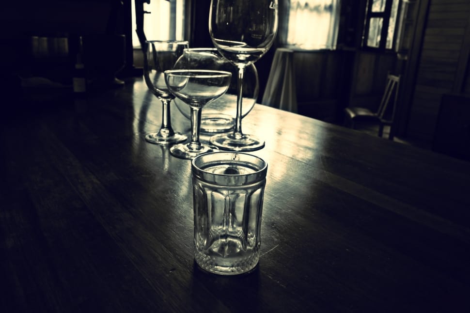 four clear glass drinking glass on black wooden table preview