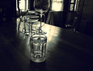 four clear glass drinking glass on black wooden table thumbnail