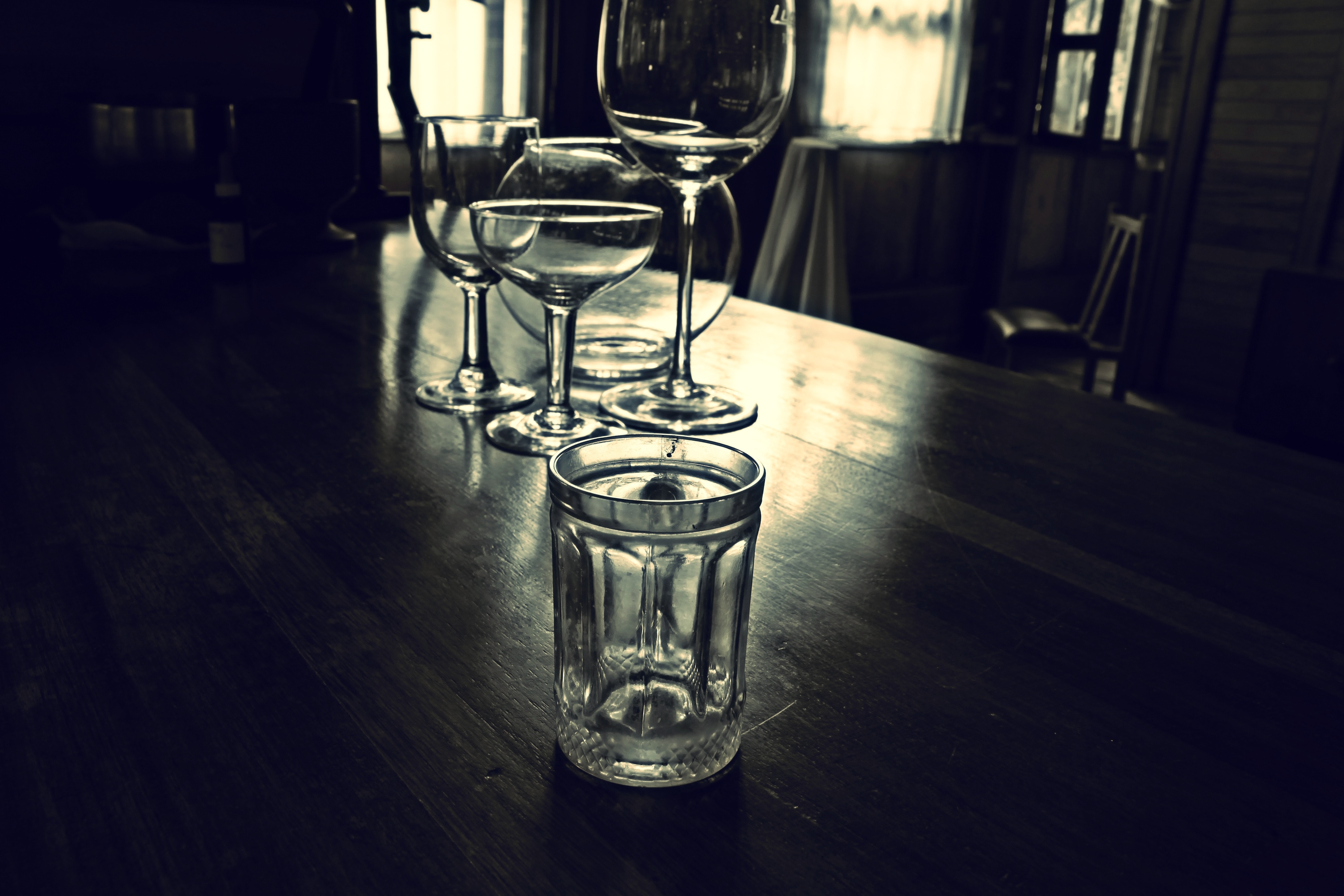 four clear glass drinking glass on black wooden table