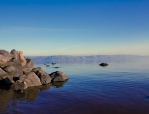 rocks on body of water under blue sky during daytime thumbnail