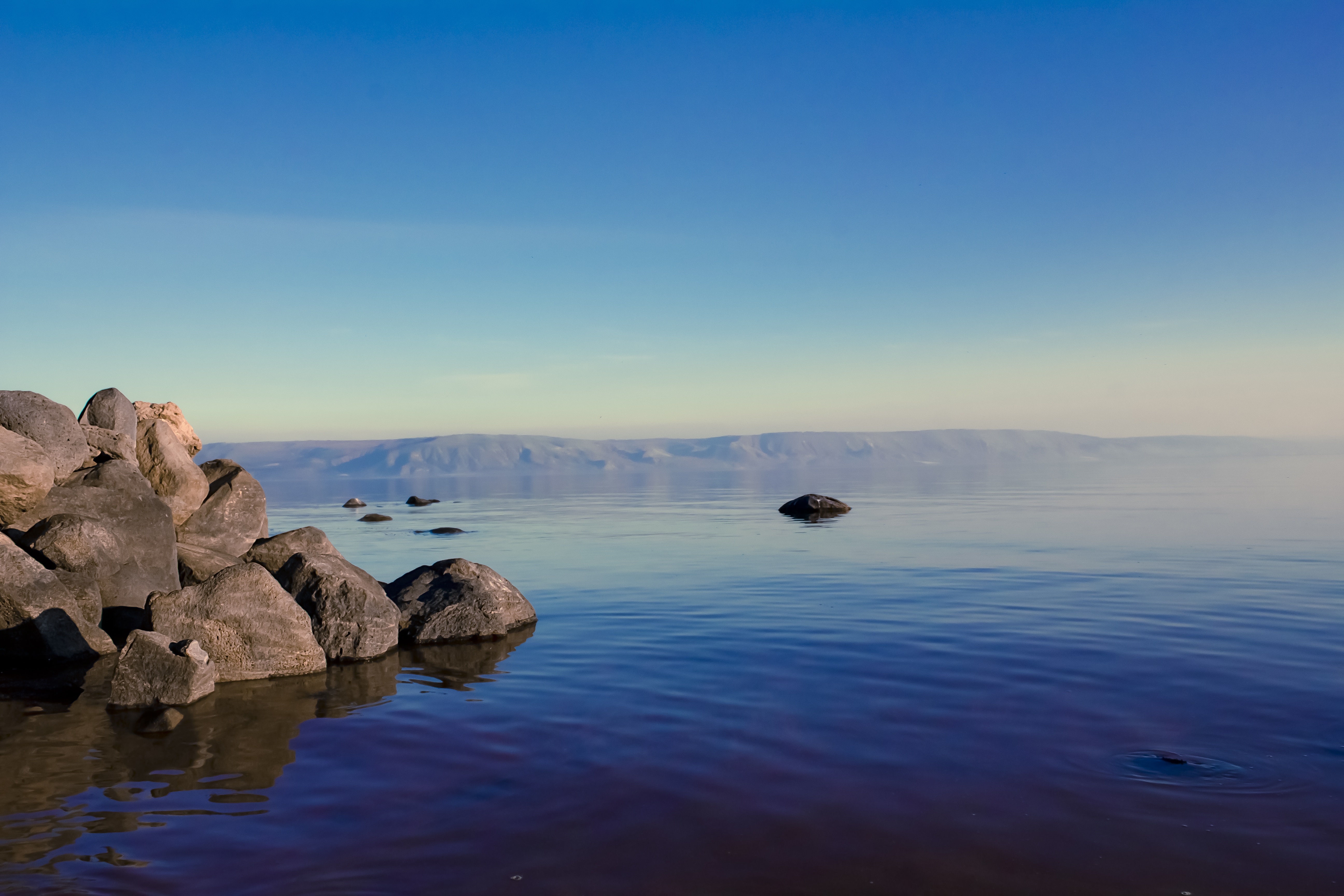 rocks on body of water under blue sky during daytime