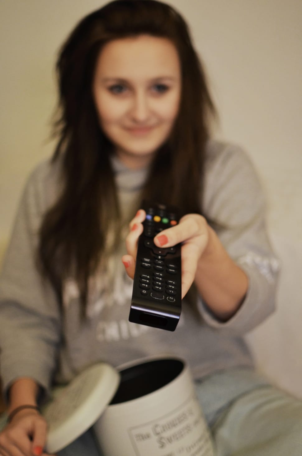 woman in gray sweater holding black remote controller preview