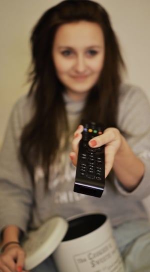 woman in gray sweater holding black remote controller thumbnail
