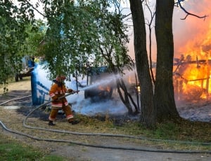 fireman holding hose in front of fire thumbnail