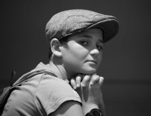 greyscale photography of boy wearing cap sleeve shirt and cap thumbnail