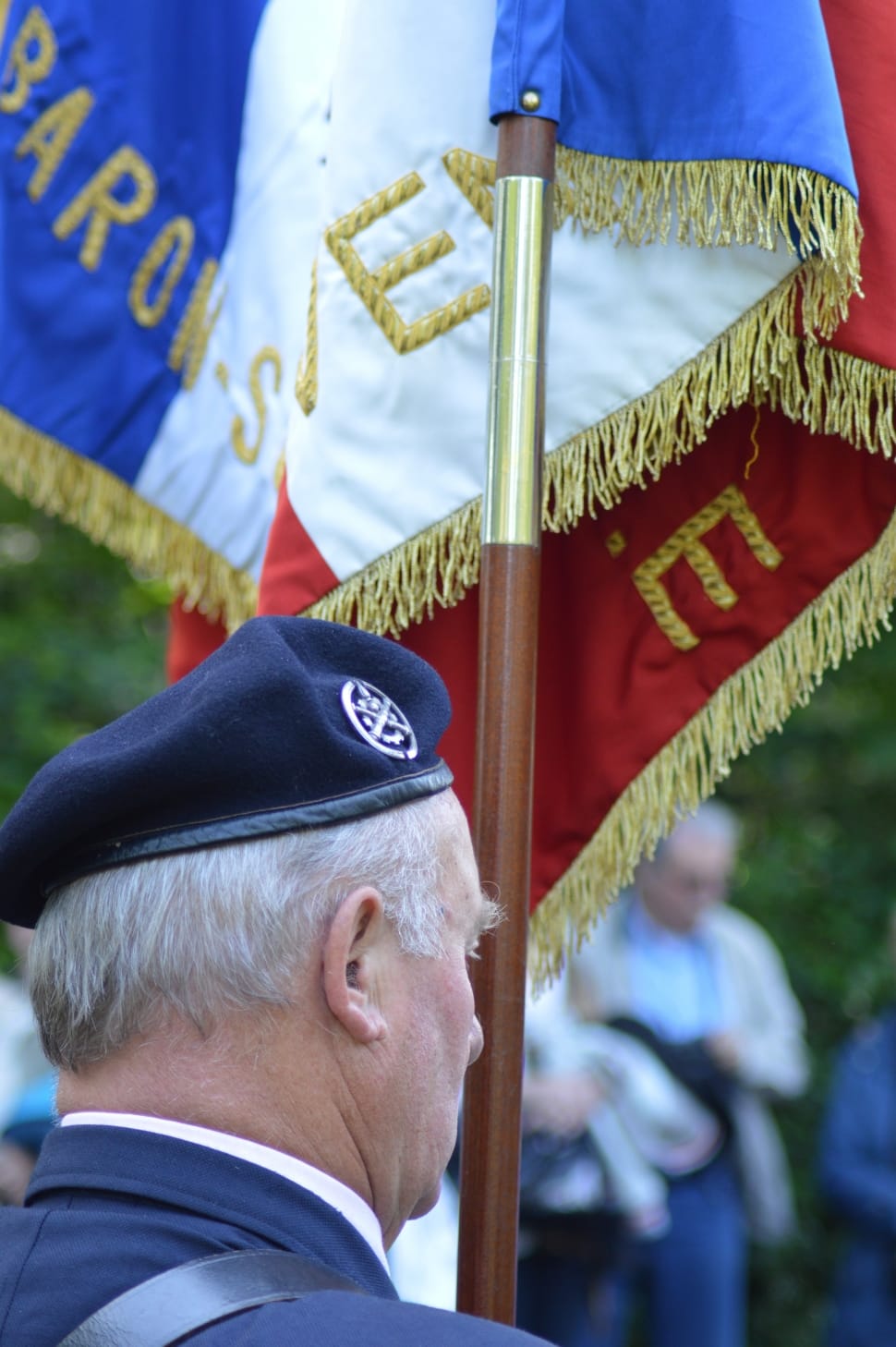 man wearing cap holding brown wooden stick of a flag preview