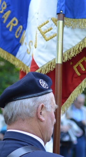 man wearing cap holding brown wooden stick of a flag thumbnail