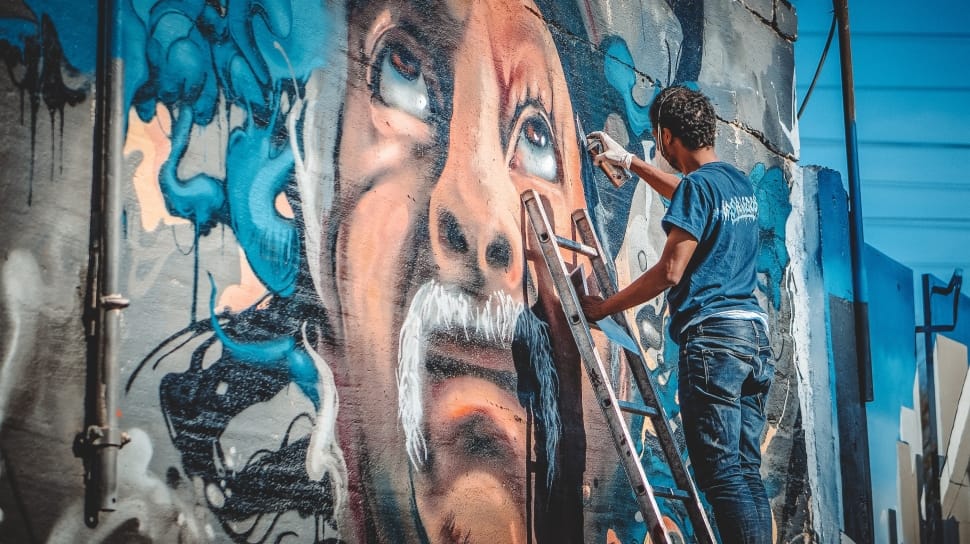 man's face mural painting; men's blue t-shirt and blue denim jeans preview