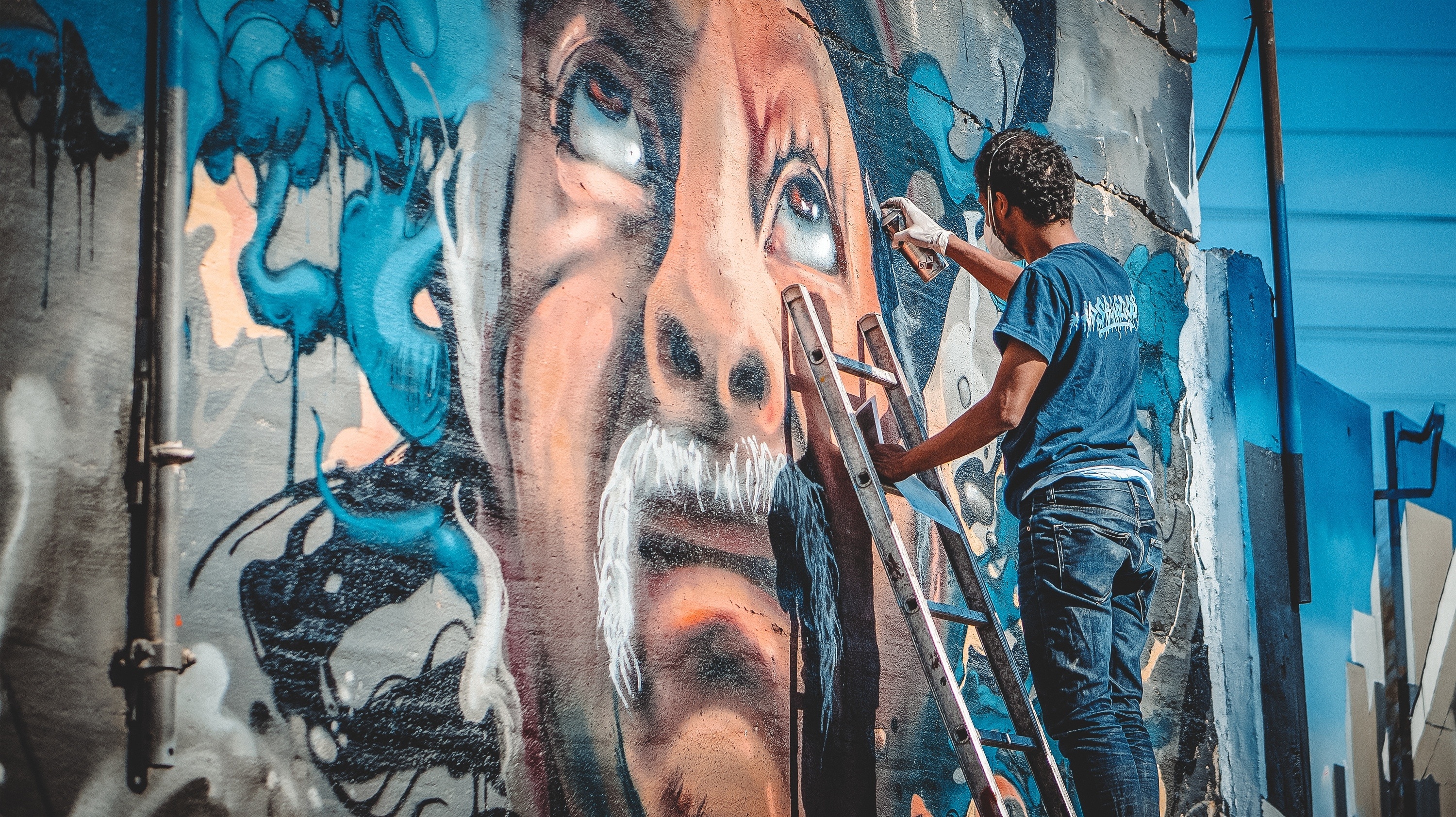 man's face mural painting; men's blue t-shirt and blue denim jeans