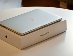 macbook pro with box on round white wooden table thumbnail