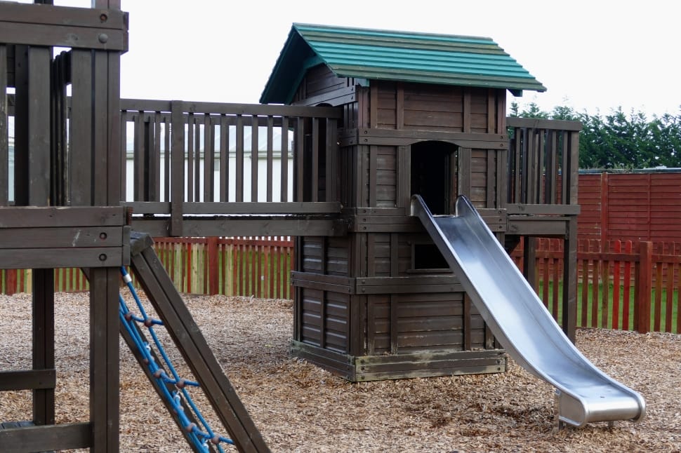 brown gray and green wooden playhouse with slide during daytime preview