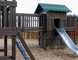 brown gray and green wooden playhouse with slide during daytime thumbnail