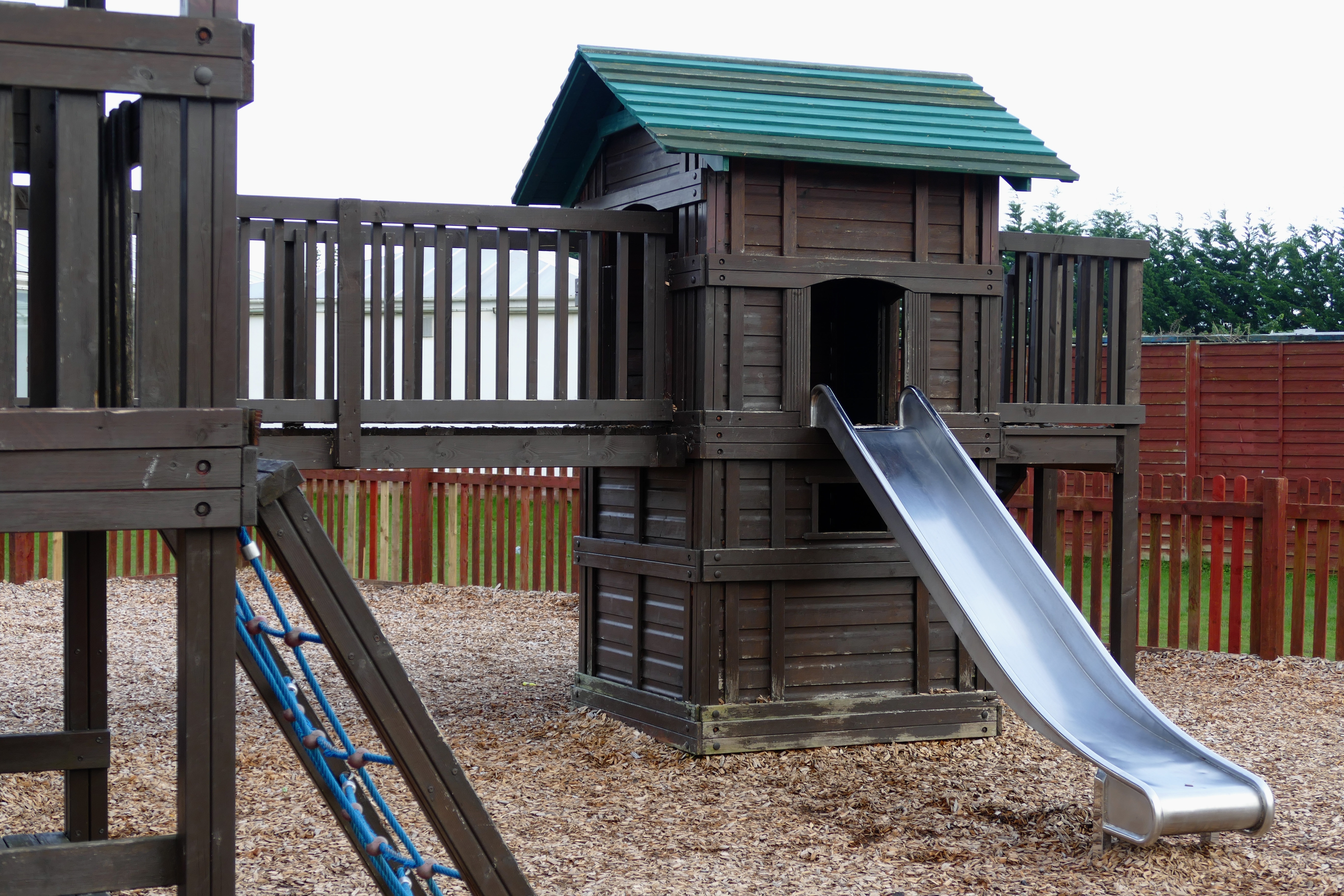brown gray and green wooden playhouse with slide during daytime