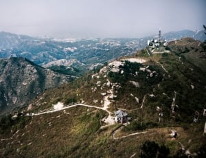 aerial view of mountain with green trees with houses on top thumbnail