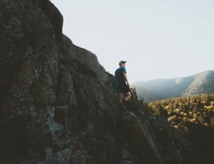 man standing on rock formation with mountain vew during daytime thumbnail