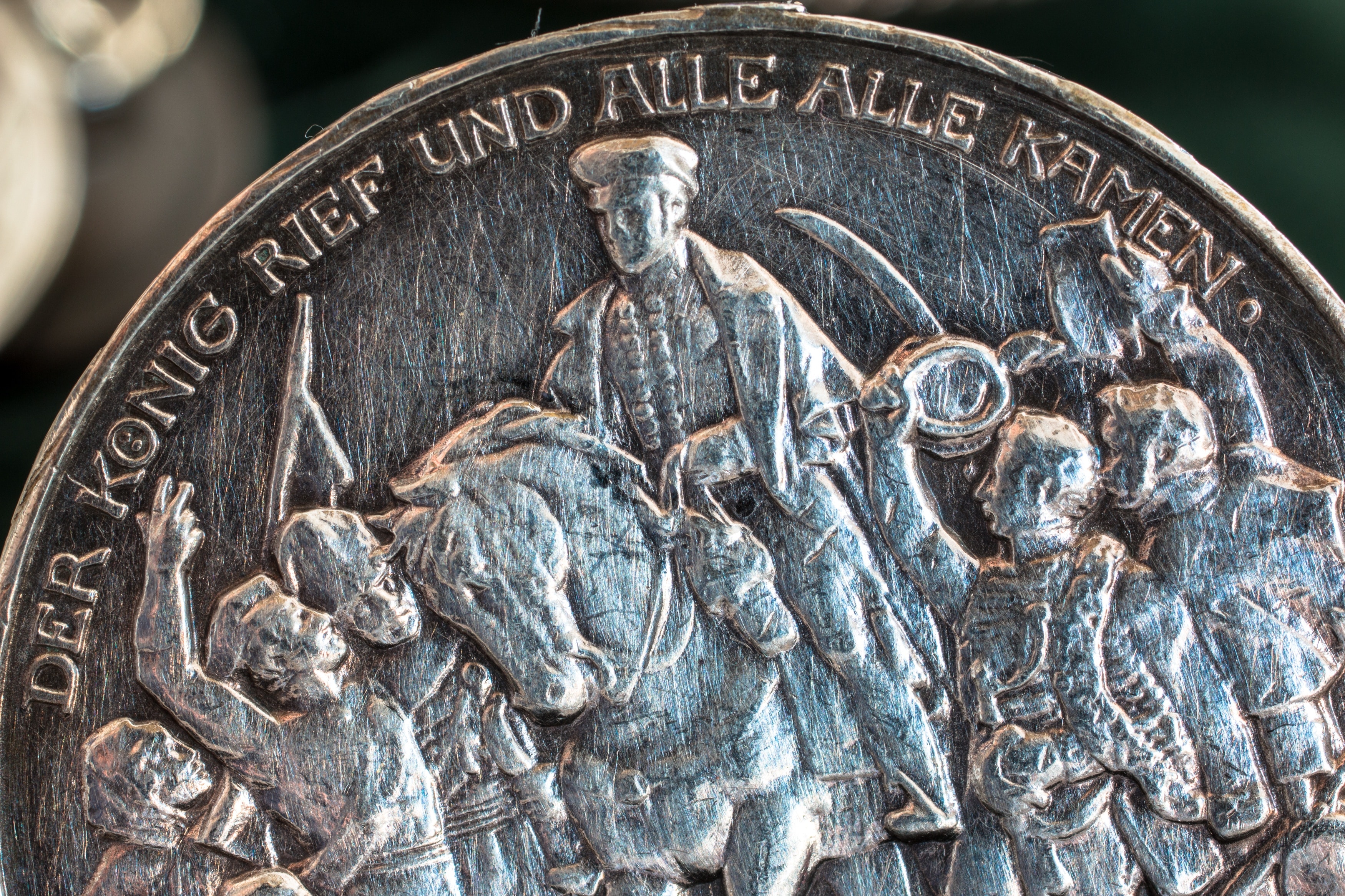 round silver coin with Der Konig Rief Und Alle Alle Kamen text