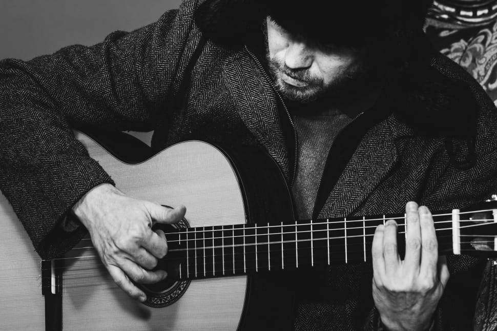 grayscale photo of man playing acoustic guitar preview