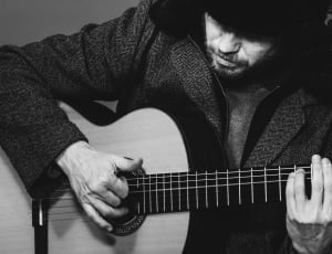 grayscale photo of man playing acoustic guitar thumbnail