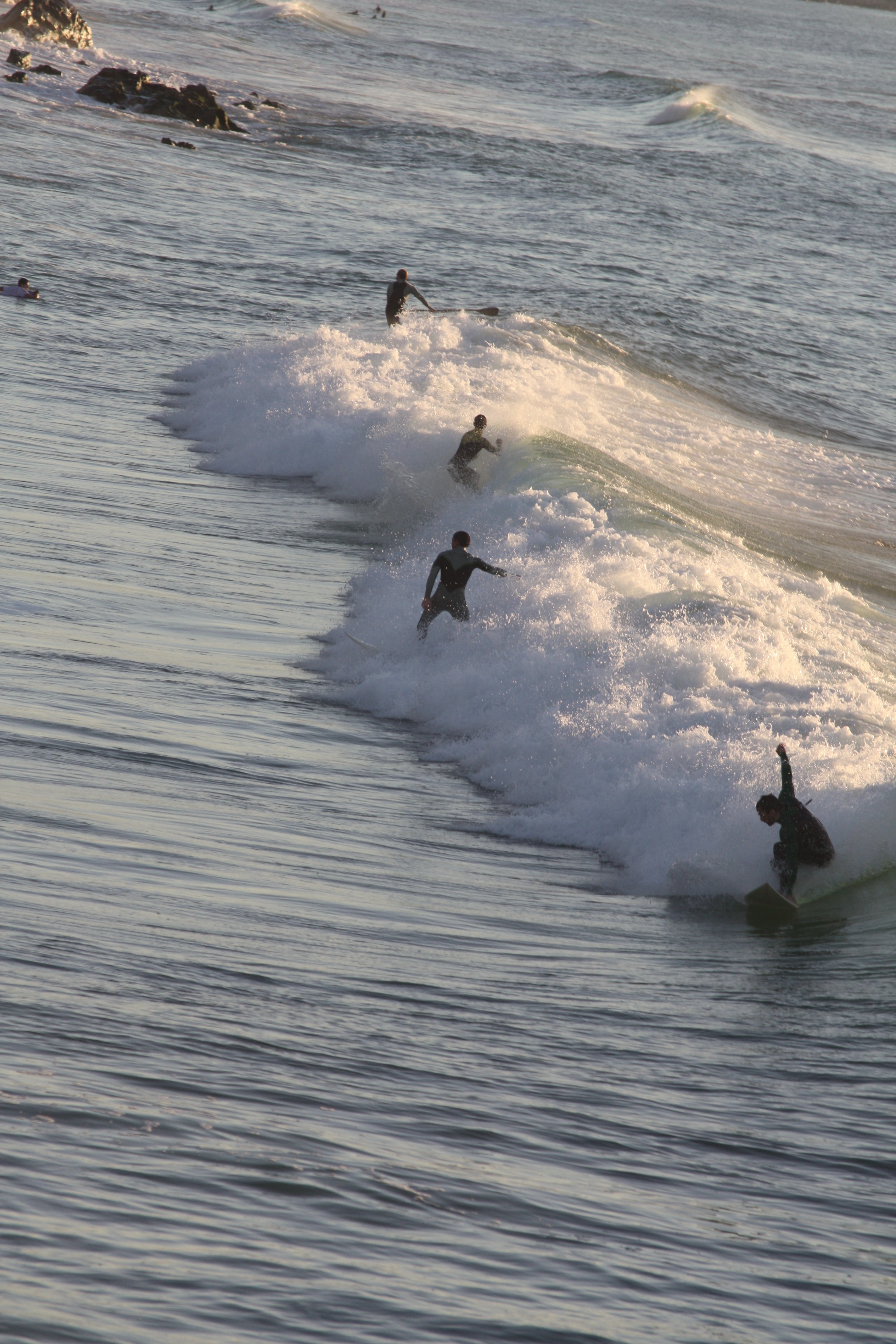 4 person surfing on waves