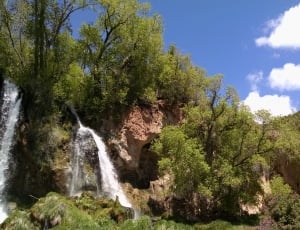 waterfalls and green leaf tree under blue sky photo thumbnail