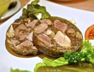 two meat dishes with green leafy vegetable and sliced tomato on white ceramic plate thumbnail