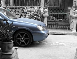 blue car in front of black metal gate outside during daytime thumbnail