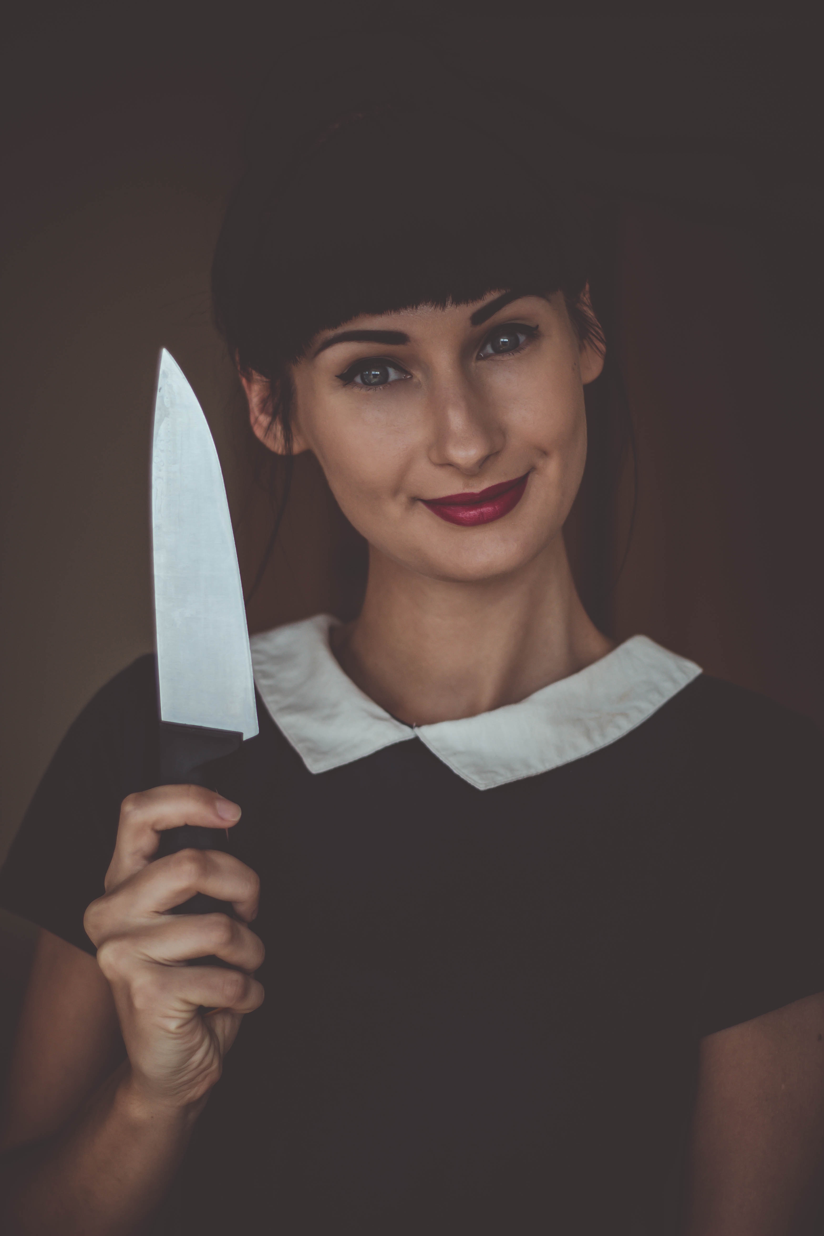 black haired woman smiling while holding a knife