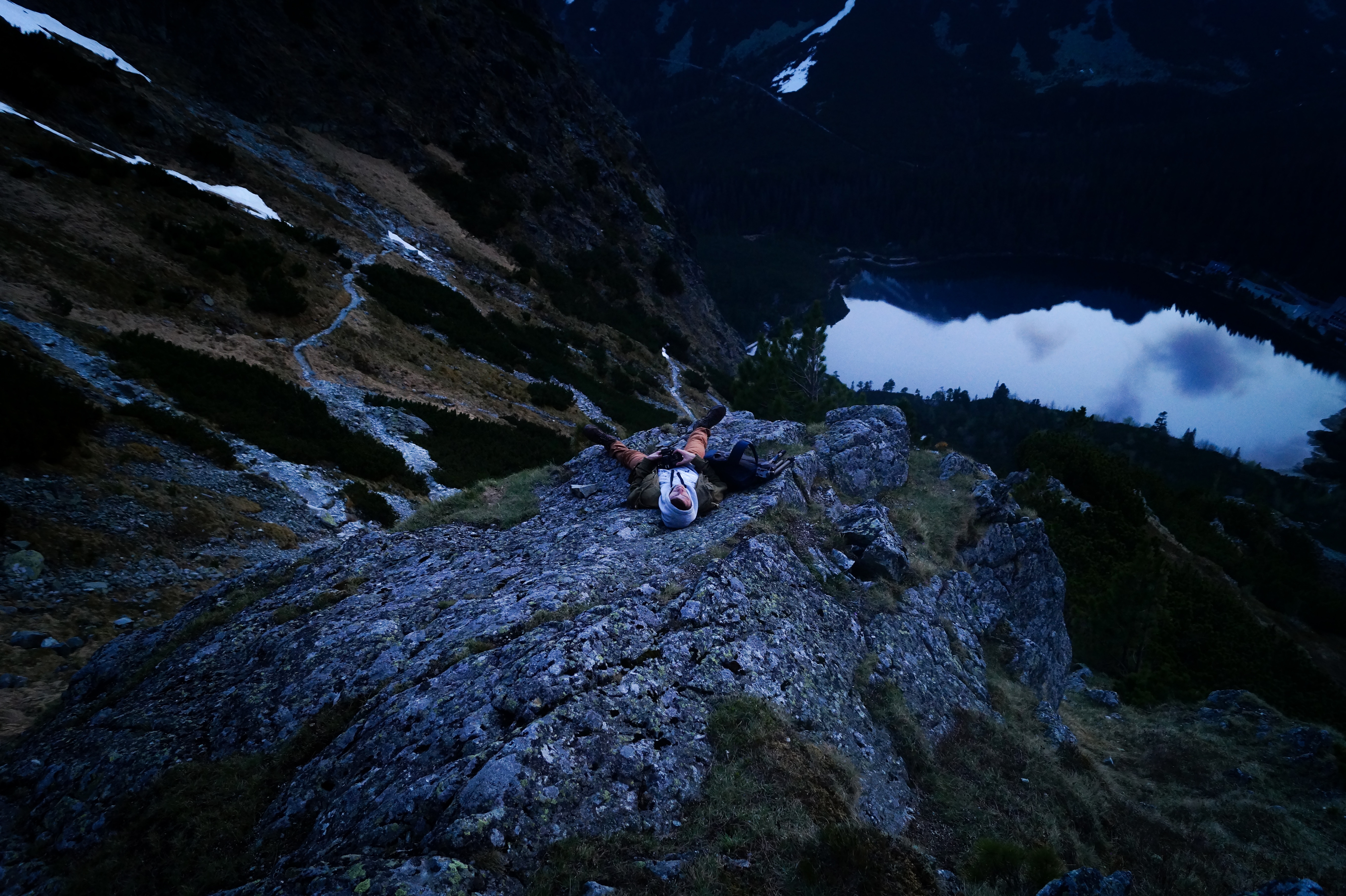 person laying on gray rock