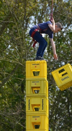boy wearing blue shirt on top of yellow plastic crates thumbnail