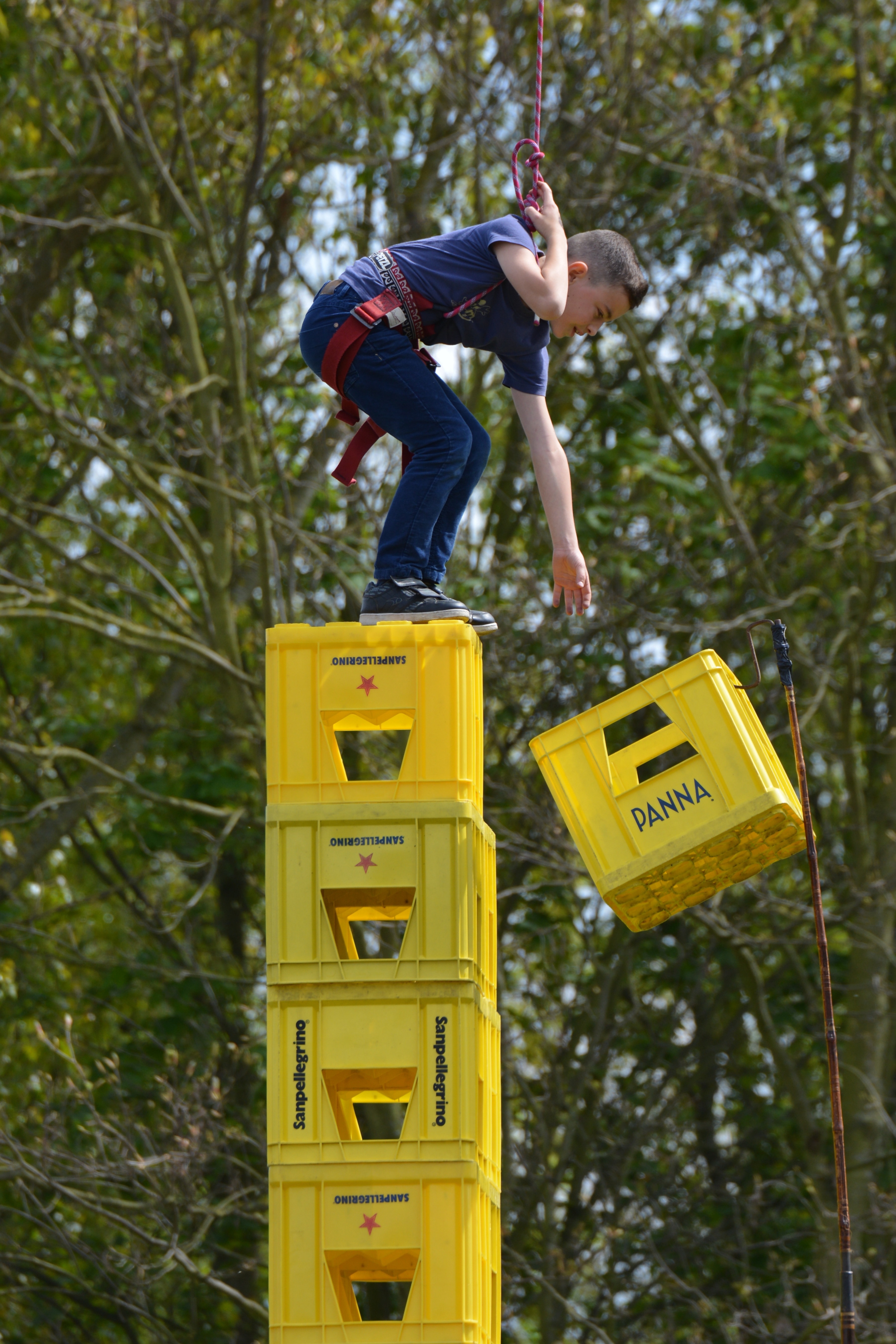 boy wearing blue shirt on top of yellow plastic crates