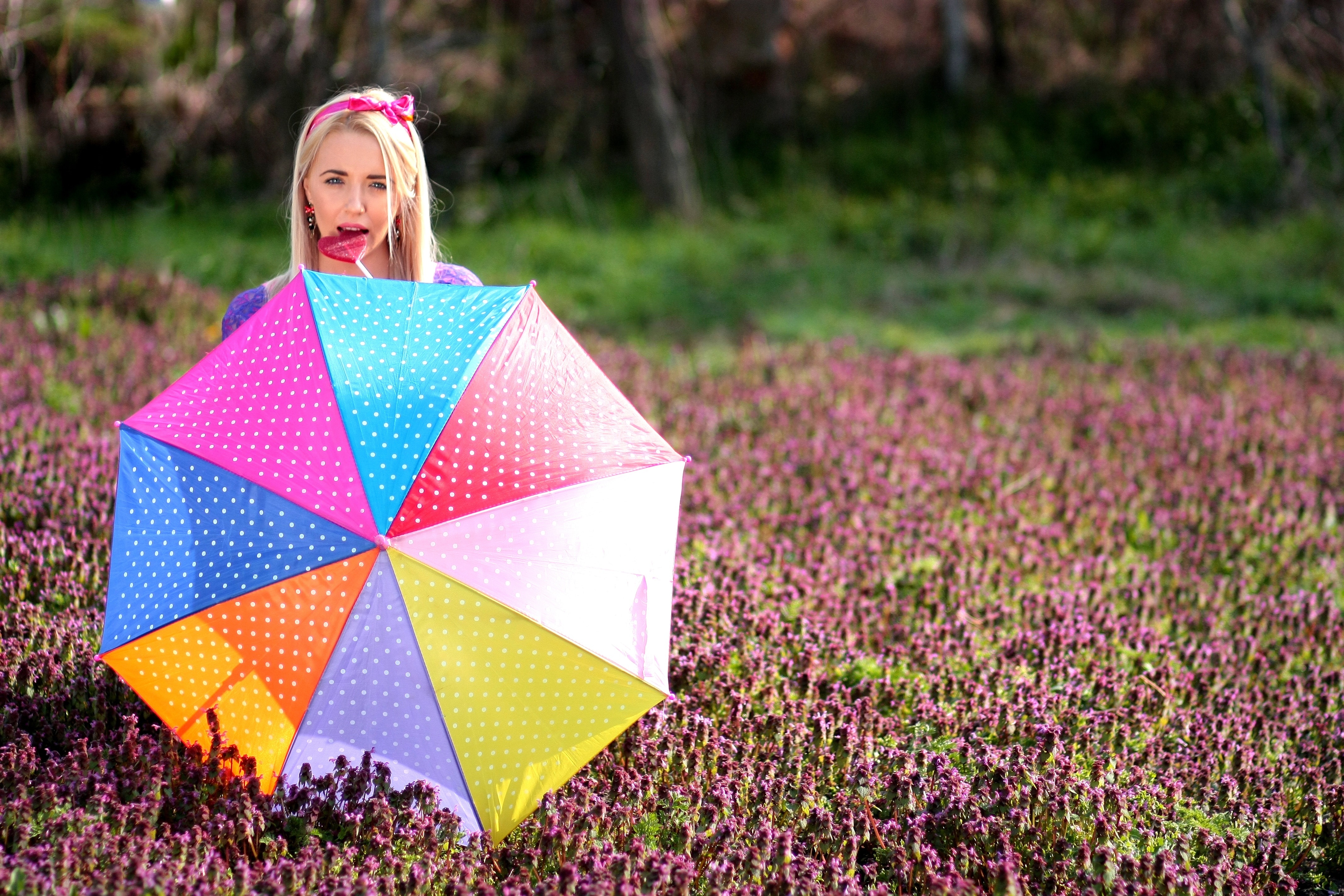 selective focus photography of woman in garden with umbrella