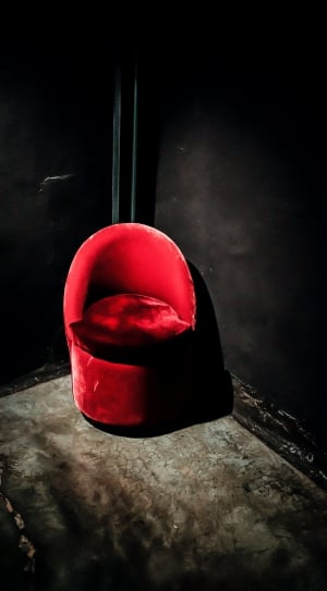 red suede chair in the corner of black wall paint room thumbnail