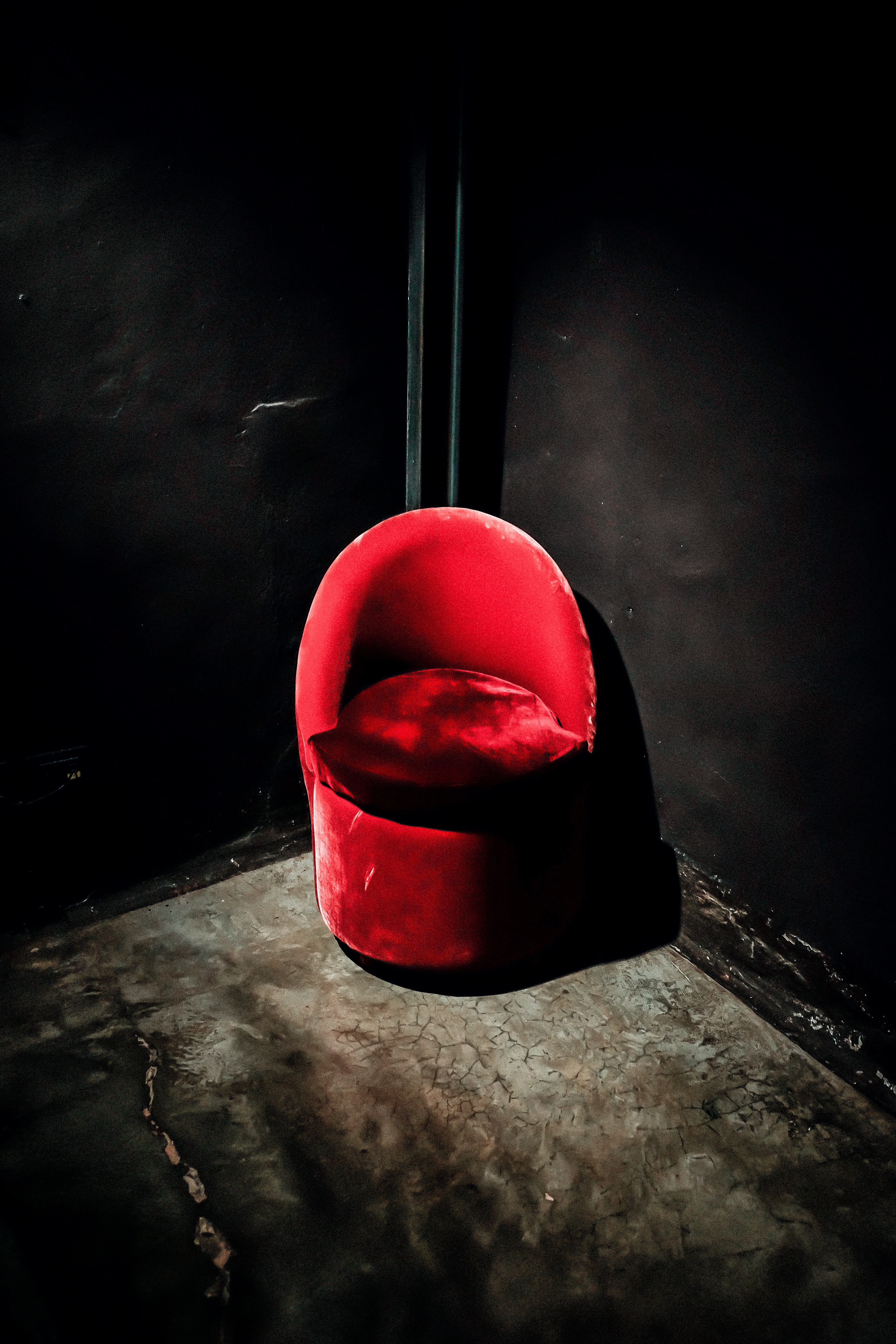 red suede chair in the corner of black wall paint room