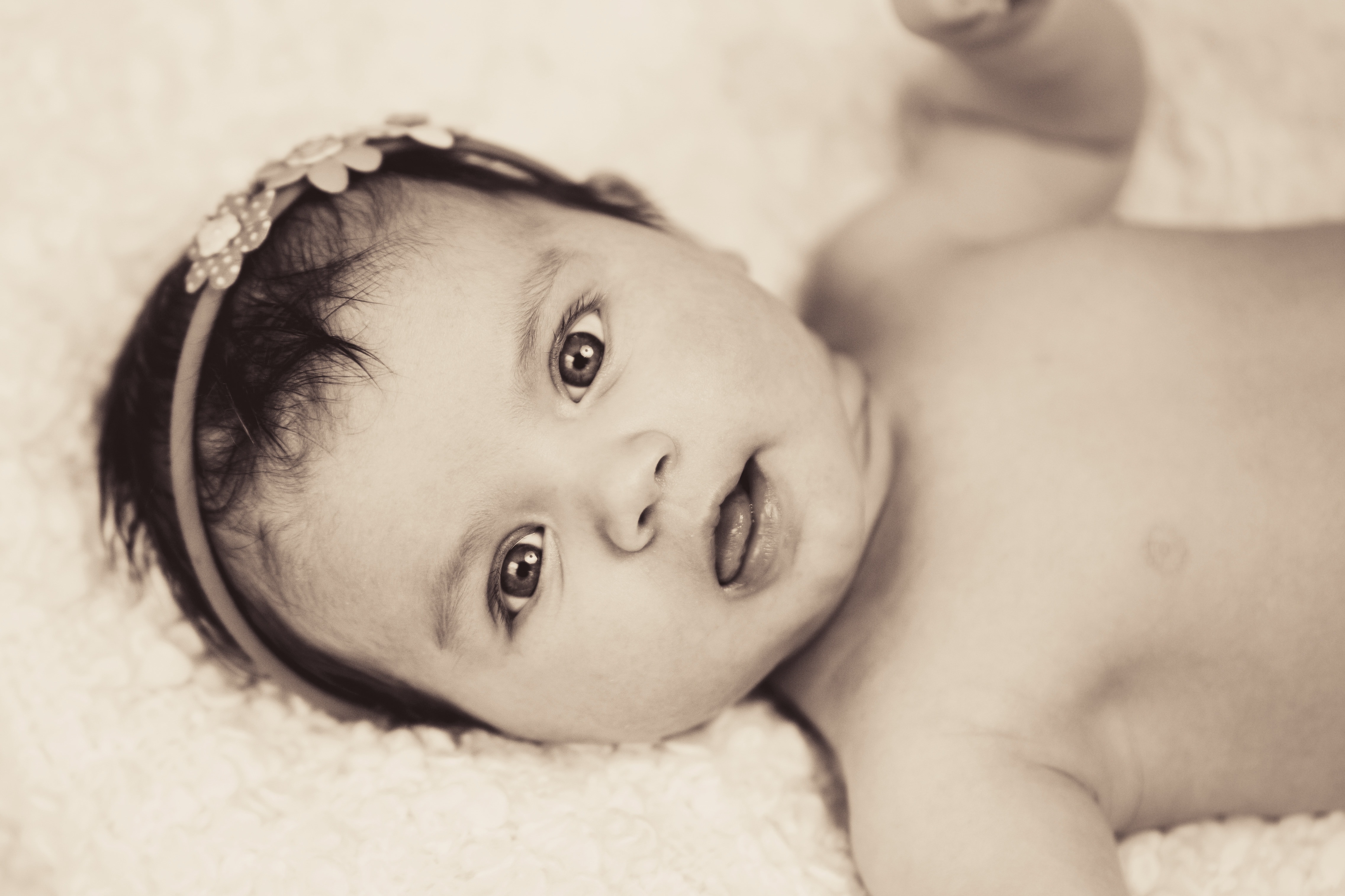 naked infant lying on white textile