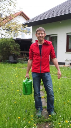 man in greenfield holding watering can during daytime thumbnail