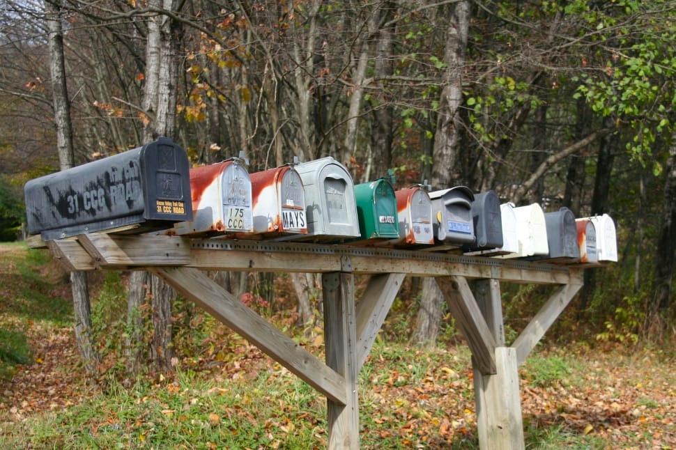 white and black metal mailboxes on brown wooden stand during daytime preview