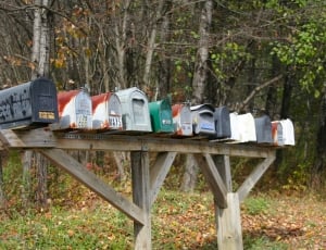 white and black metal mailboxes on brown wooden stand during daytime thumbnail