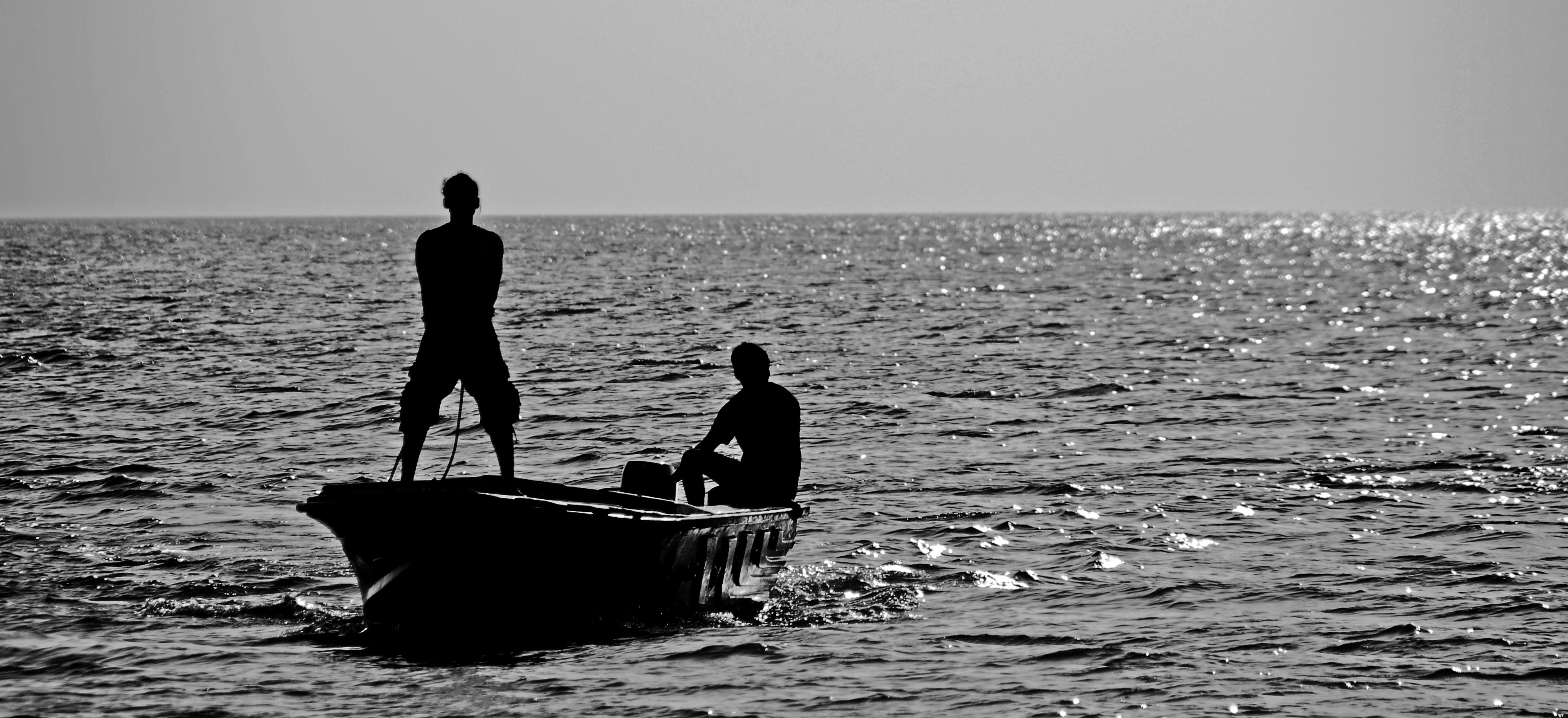 silhouette of 2 man in boat