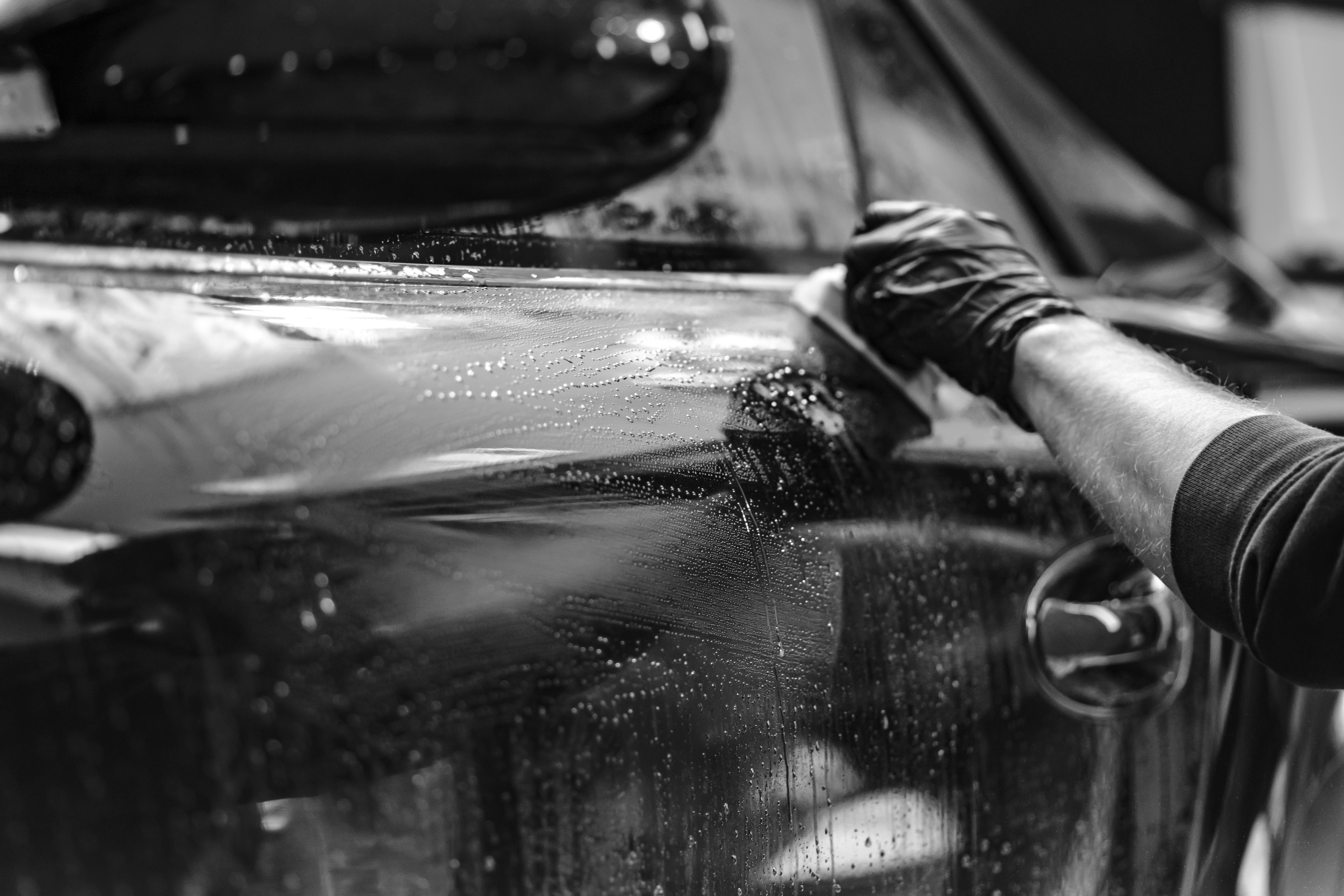 gray scale photo pf person cleaning car