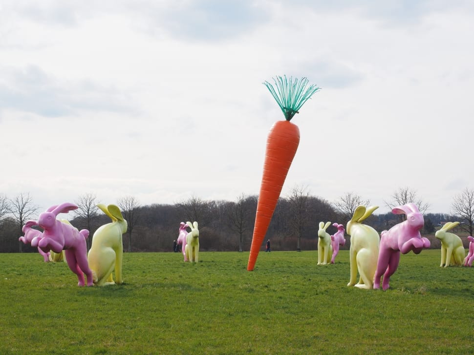 rabbit statues and carrot statue on green grass field preview