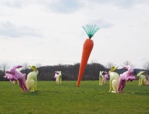 rabbit statues and carrot statue on green grass field thumbnail