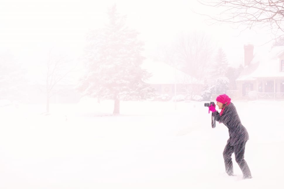 woman using black dslr camera taking a photo of tree covered with snow preview