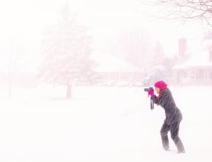 woman using black dslr camera taking a photo of tree covered with snow thumbnail