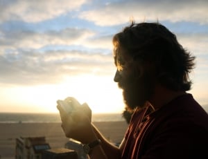 man wearing red shirt holding device during sun set thumbnail