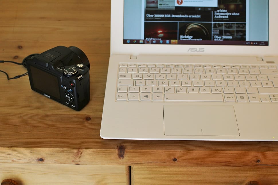 white Asus laptop near SLR camera preview