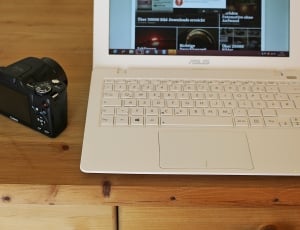 white Asus laptop near SLR camera thumbnail